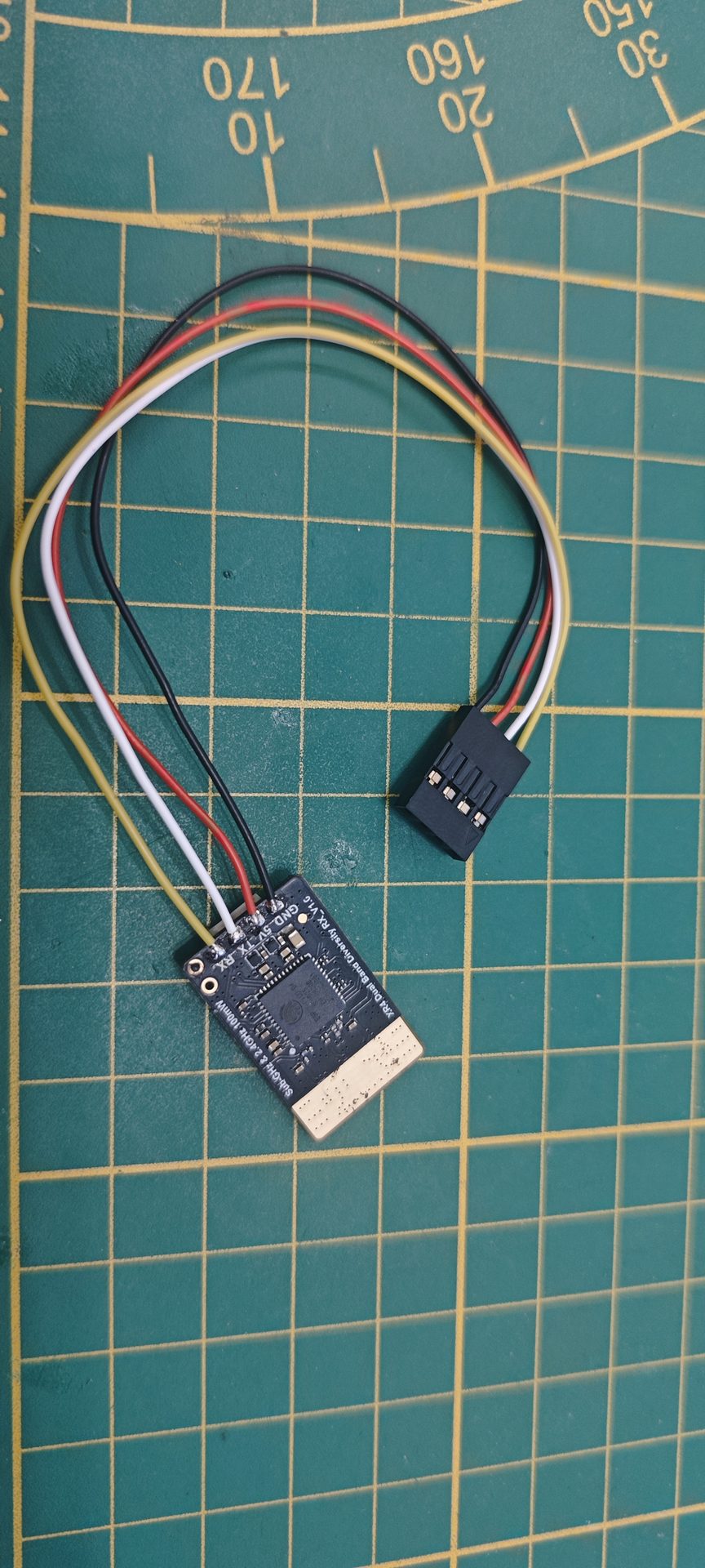 Zbliżenie płytki odbiornika RadioMaster XR4 Dual Band Diversity V1.0 z widocznymi wyprowadzeniami GND, 5V, TX, RX